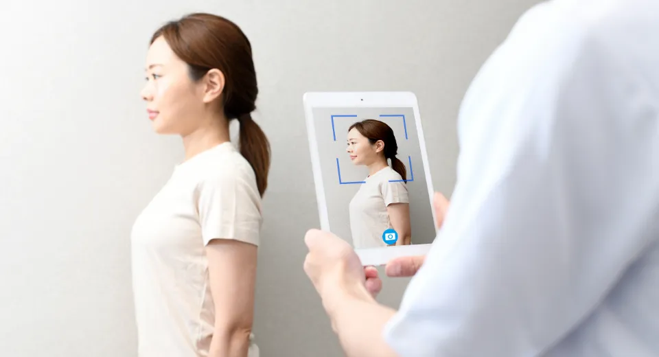 鏡を見て体型を気にしている女性
